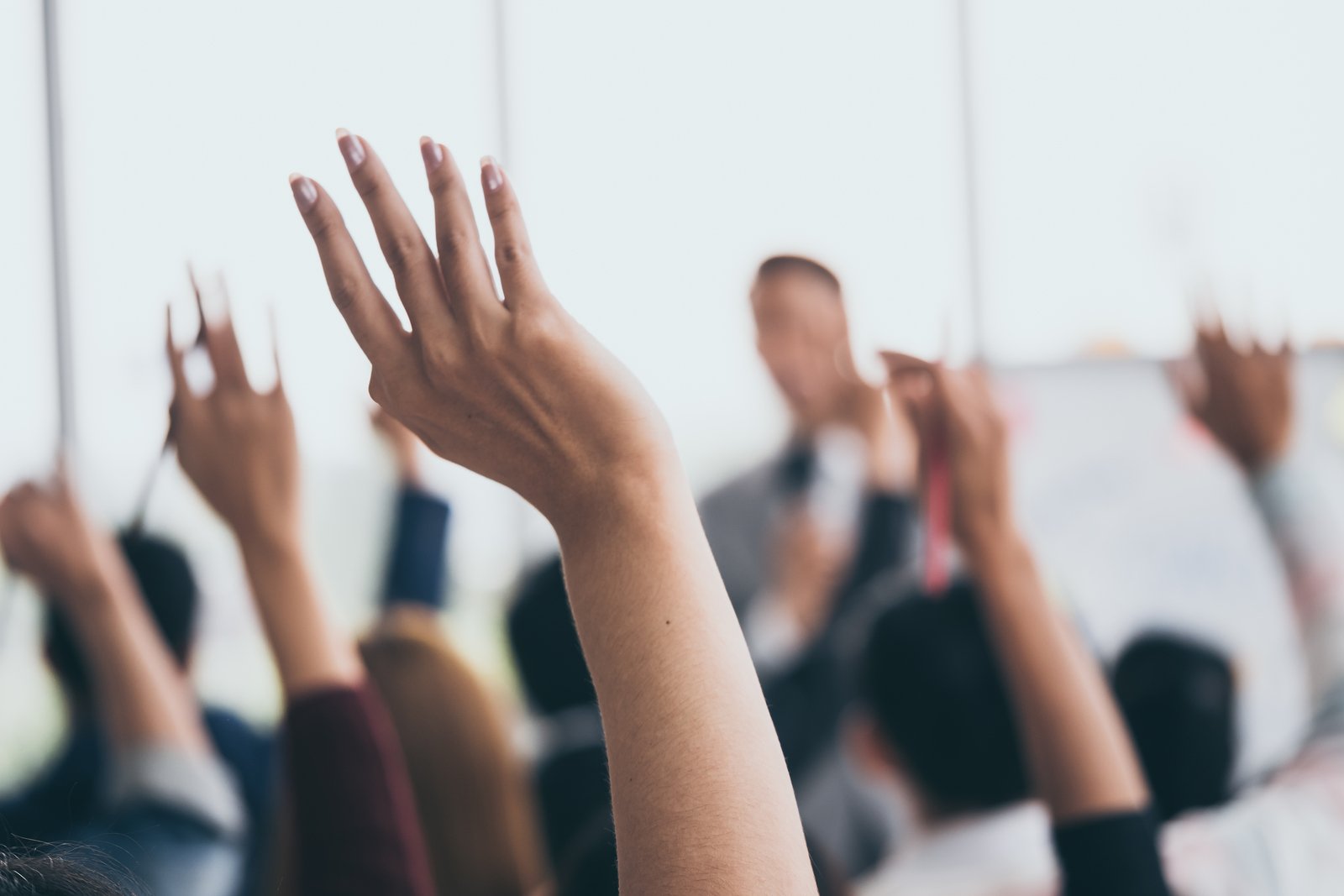 bigstock-Audience-Raising-Hands-Up-Whil-259416742